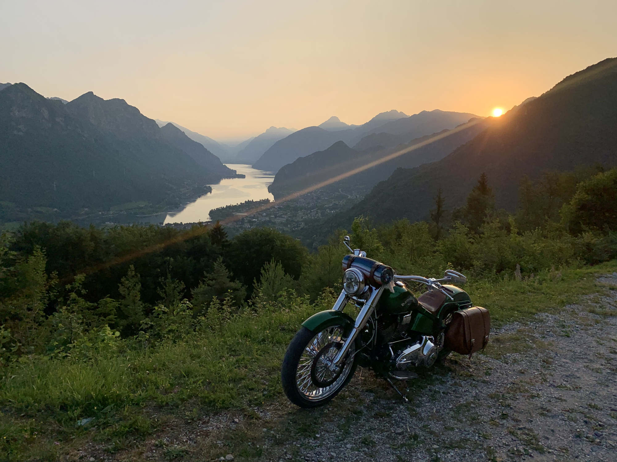 A picture of a green motorcycle with the sunset in the background.
