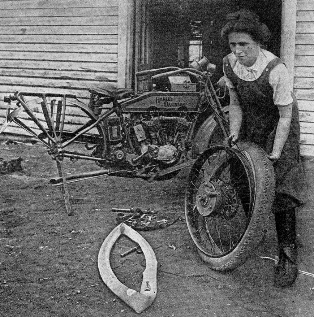 Susan Lang changing a tire on a Harley-Davidson.