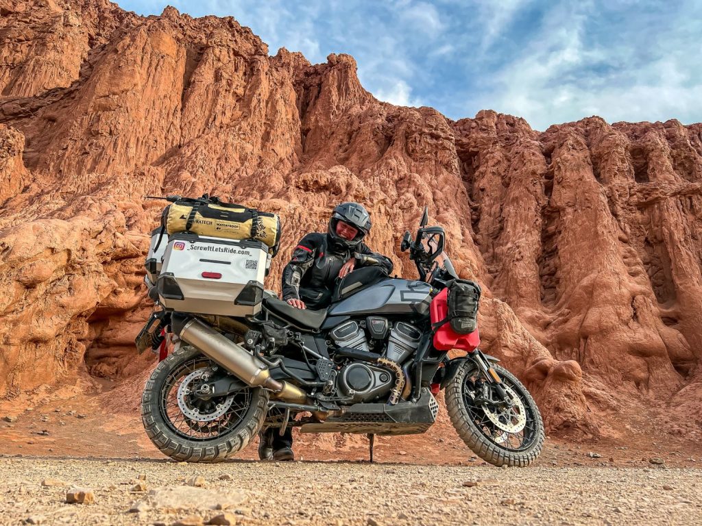 Ela Kedzior posing with her motorcycle by a rocky canyon in Argentina