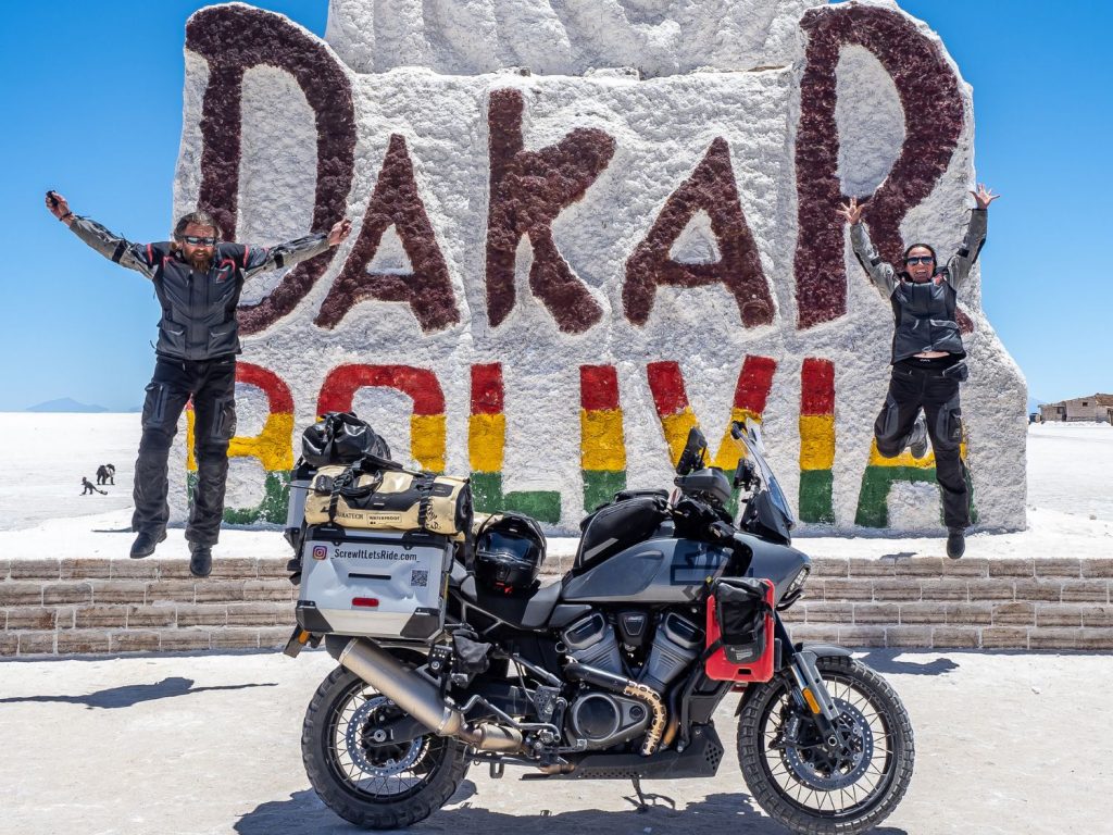 Ela and Greg Kedzior jumping in front of a monument on the Dakar saltflats.