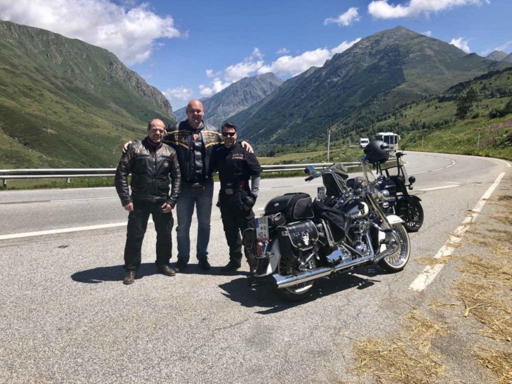 A picture of three people standing next to a motorcycle.