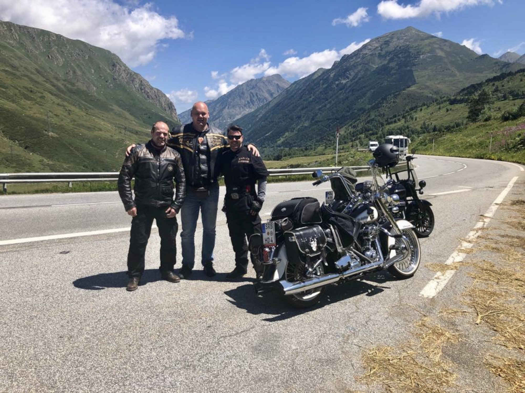 A picture of three people standing next to a motorcycle.