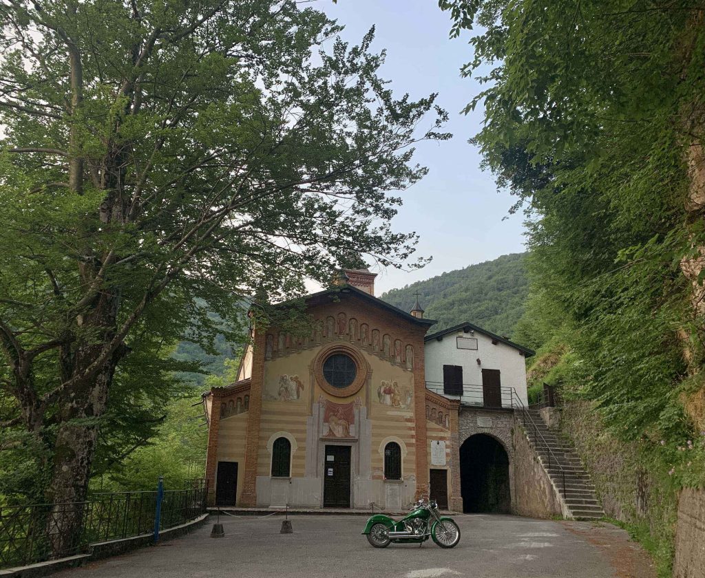 A picture of a green motorcycle in front of a chapel.