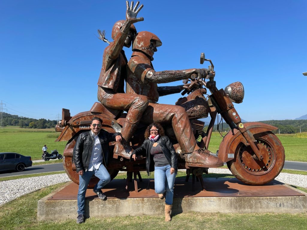 A picture of Antonio and Pamela in ront of a Harley-Davidson sculpture.