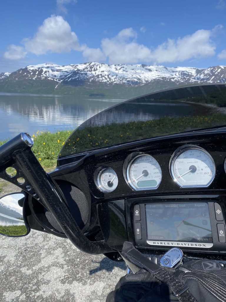 A picture of a motorcycle dashboard against a backdrop of mountains.