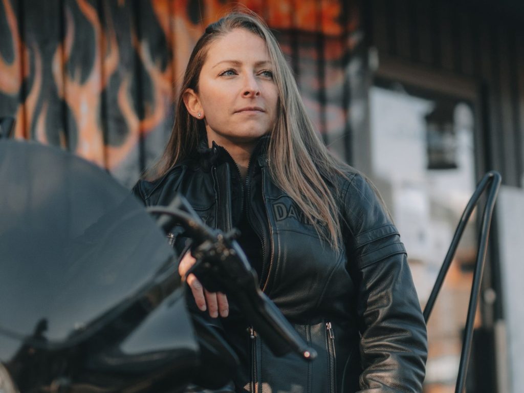 ANDRA NEDELCU in her motorcycle leathers, posing with her motorcycle.