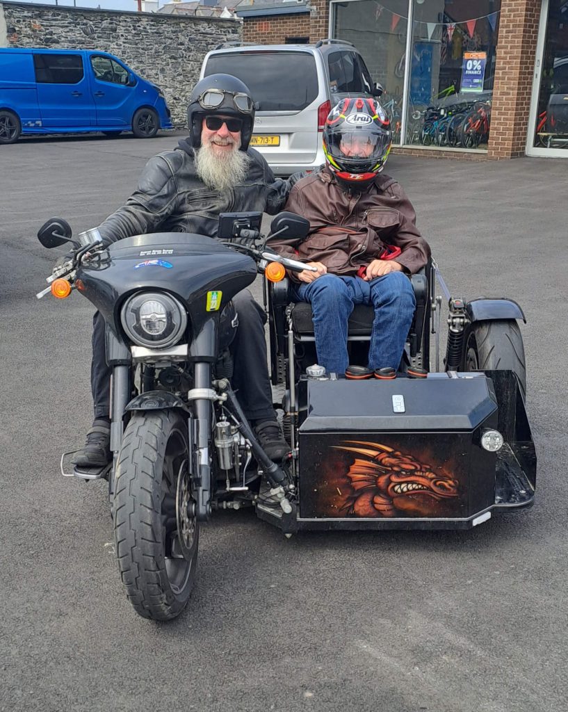 A picture of Bob on his motorcycle, with his friend in the sidecar.