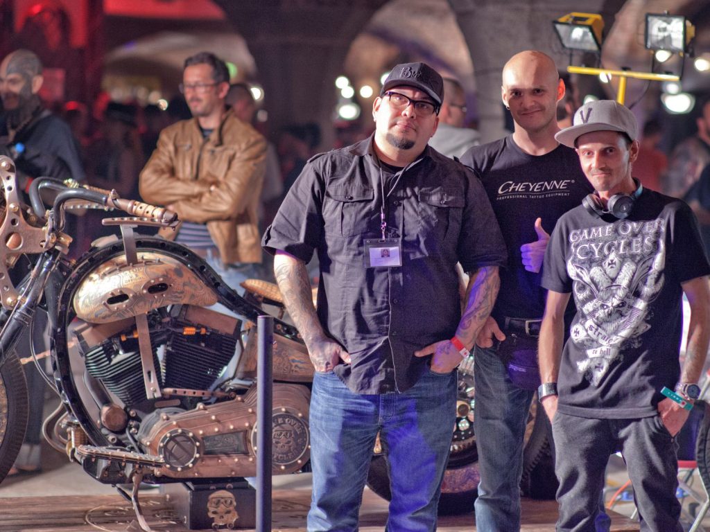 A trio of tattoo artists who have worked on a Harley-Davidson.