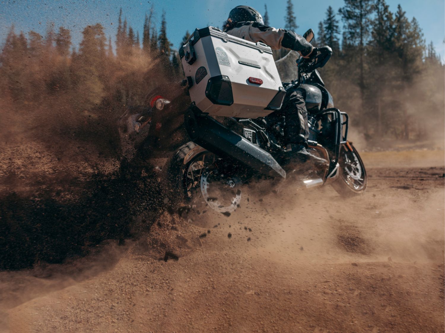 A motorcyclist kicks up dirt and dust on an off-road track.
