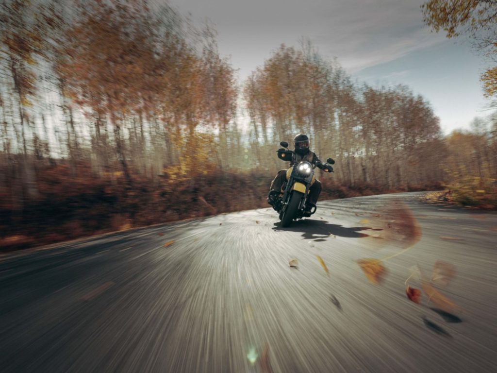 A motorcyclist rides on a road during fall.